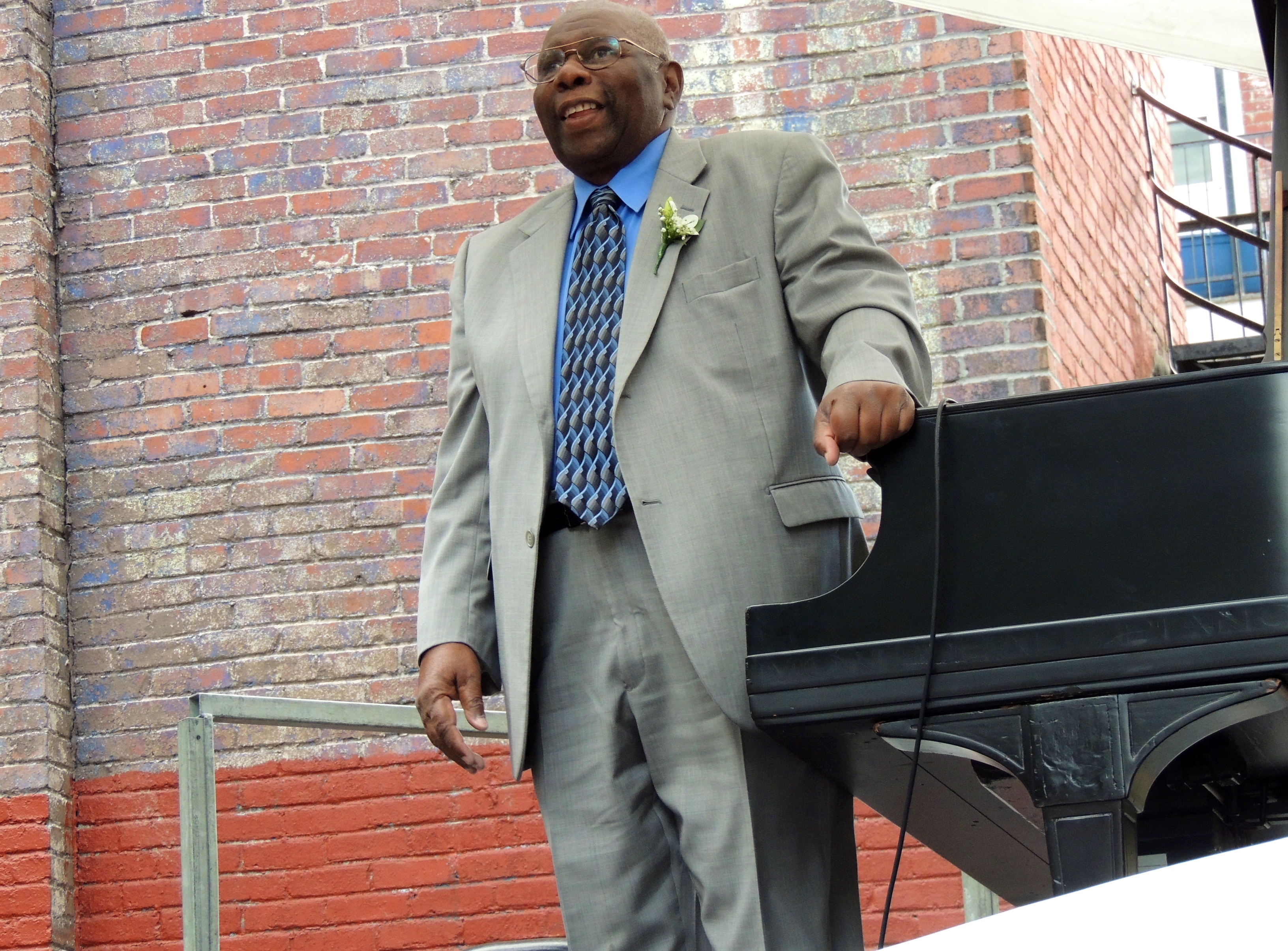Picture of Oliver Jones standing next to a piano.